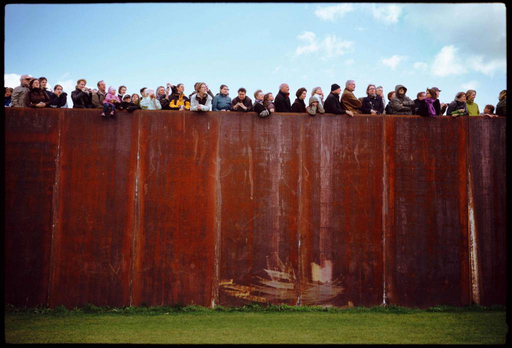 Spectators on top a big rusty wall just like being on a ship in Berlin